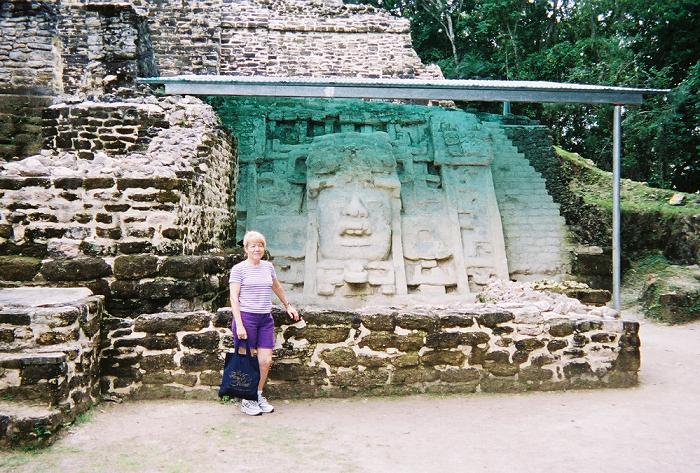 Mary standing in front of the Mask location on the right hand side of the Maya Runin of Lamanai in Belize